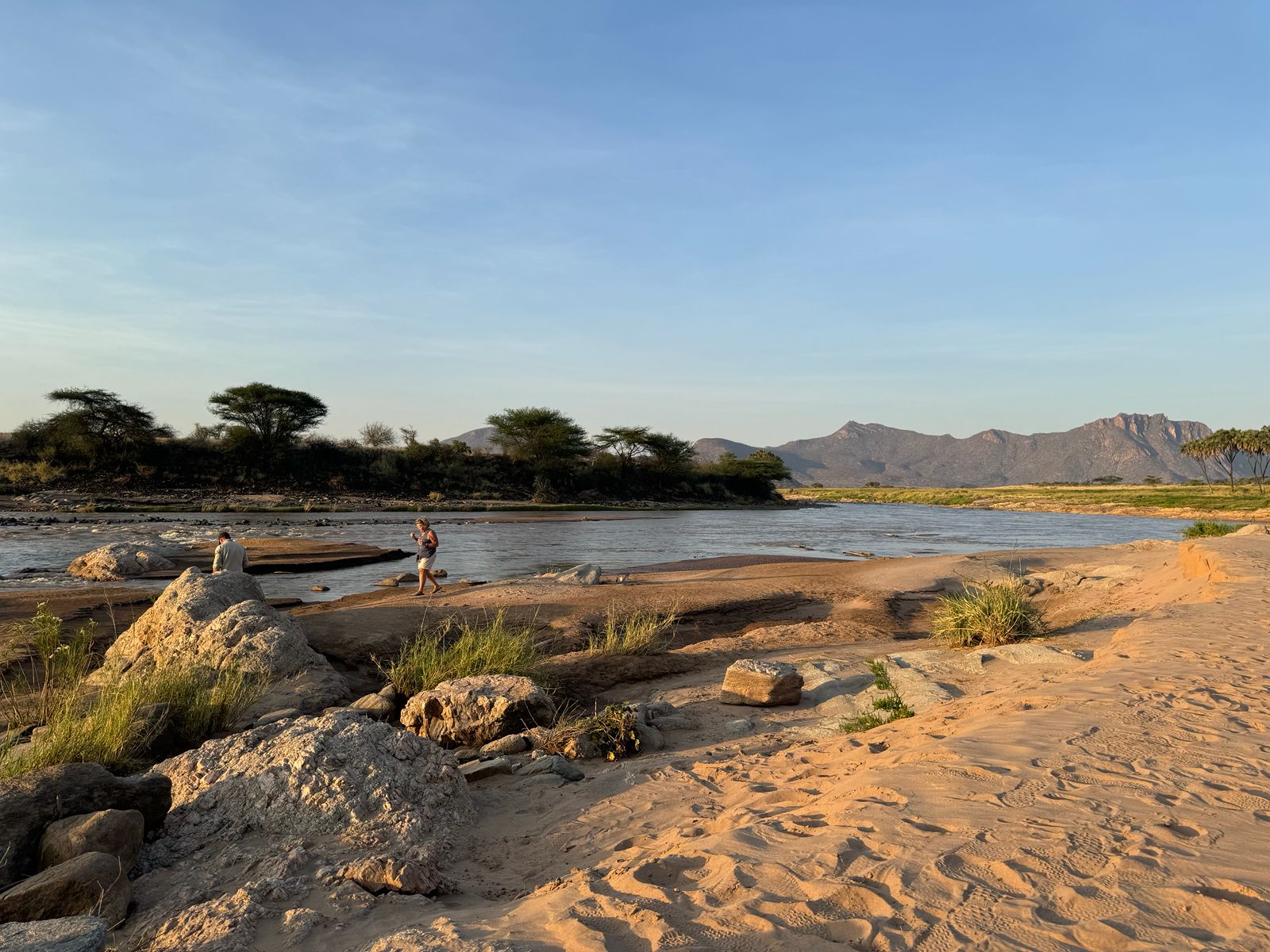 Travellers watching sunset from a rocky overlook above the Laikipia plains