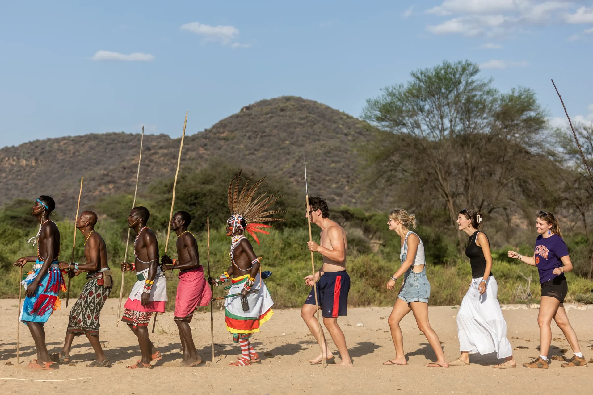 Samburu warriors leading a family in a walking dance through the bush