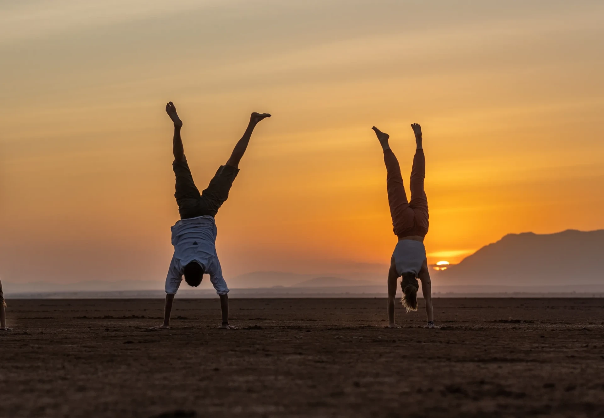 Couple doing handstands together at sunset on the open plains