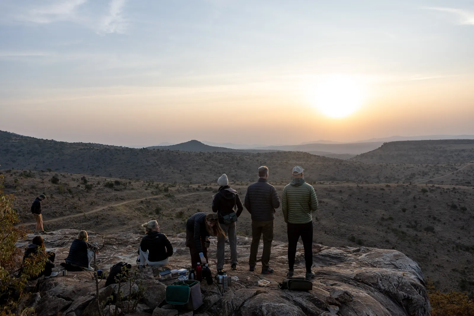 Family and guides watching sunset from a rocky outcrop