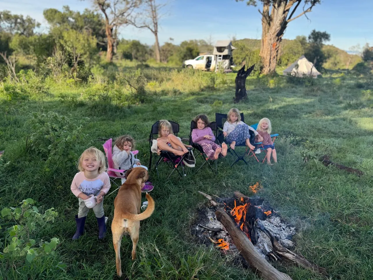 Children gathered with the camp dog around a fire at fly-camp