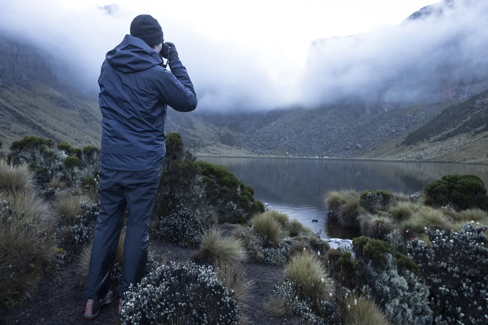 Photographer at a misty alpine tarn on Mount Kenya