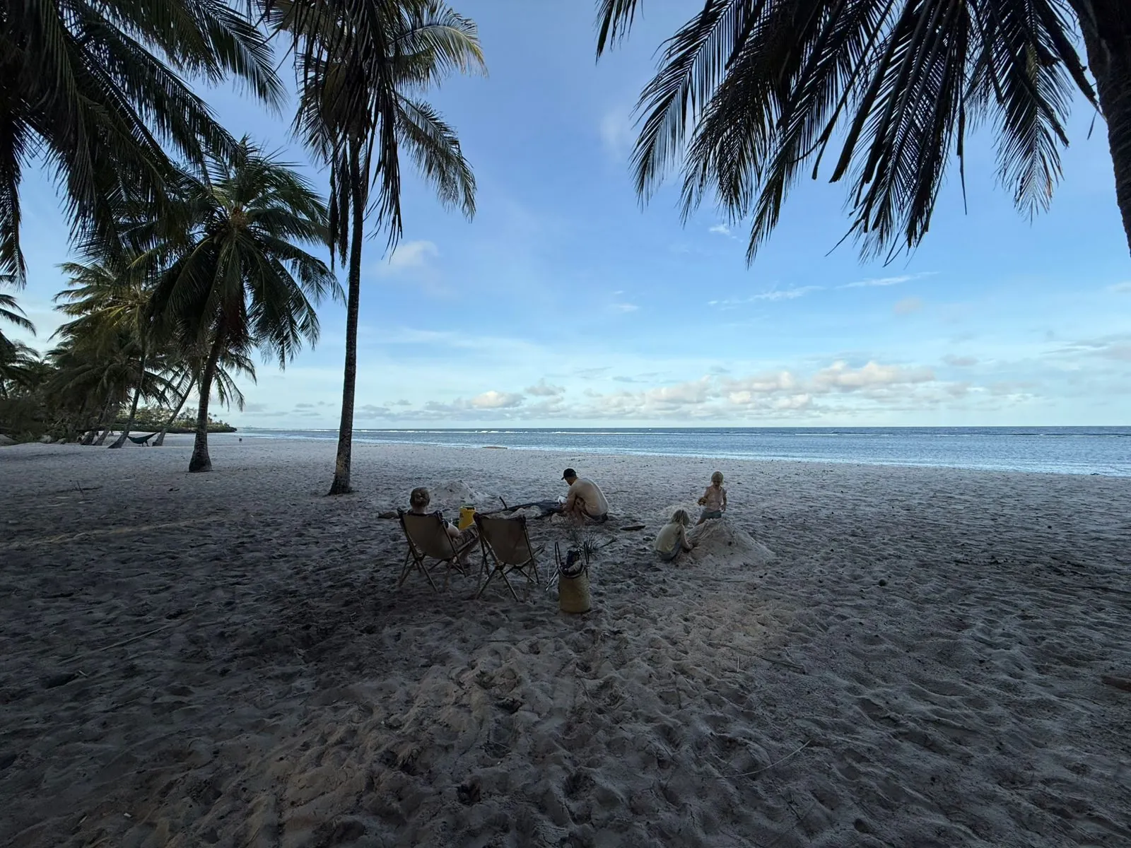 Family relaxing on a palm-lined Kenyan beach at golden hour